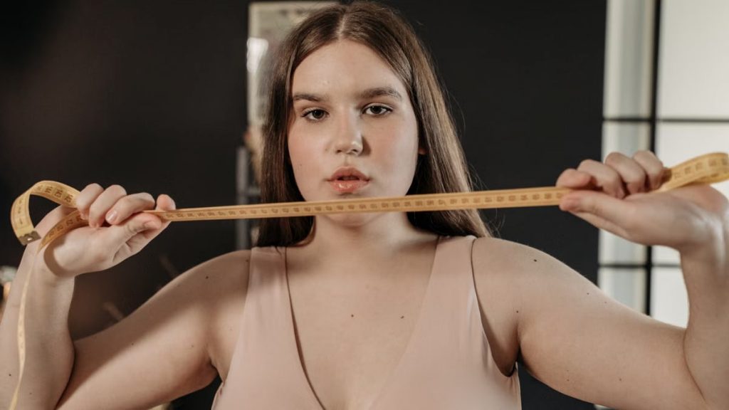 Portrait of a confident woman holding a tape measure, symbolizing self-care and body positivity.